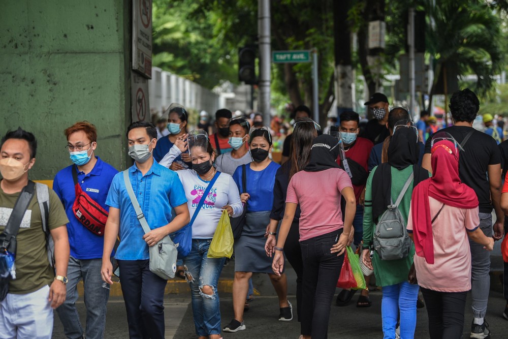 Orang-orang memakai masker dan pelindung wajah untuk melindungi diri dari virus coronavcovid-19 menyeberang jalan di Manila pada 7 September 2021. AFP/TED ALJIBE
